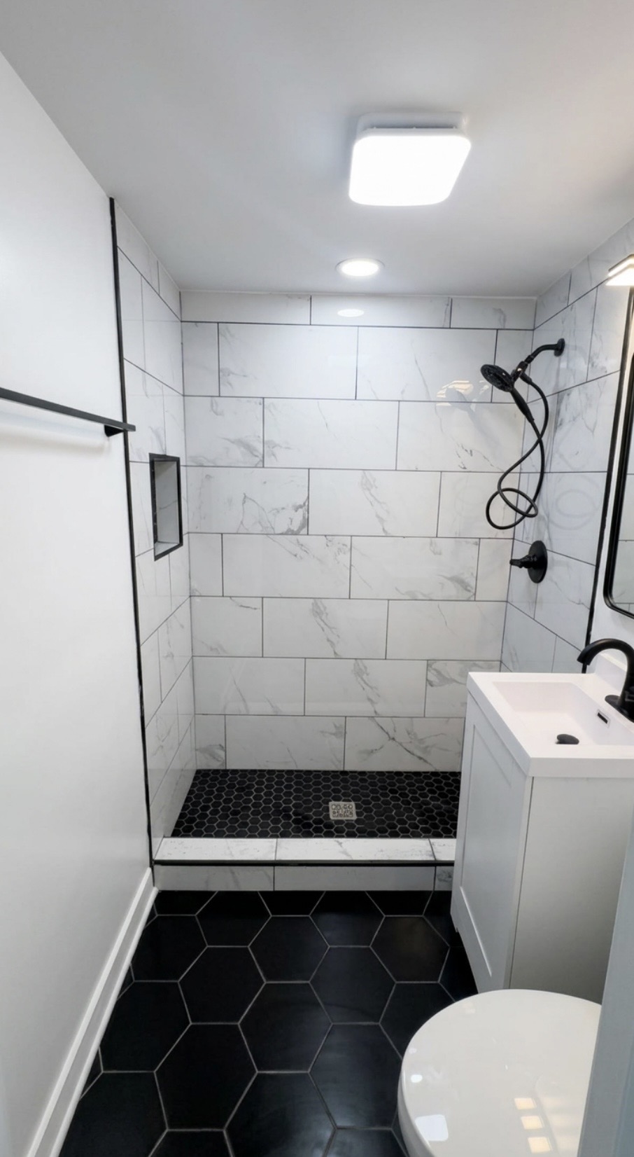Tiled walk-in shower with black hexagon floor tile