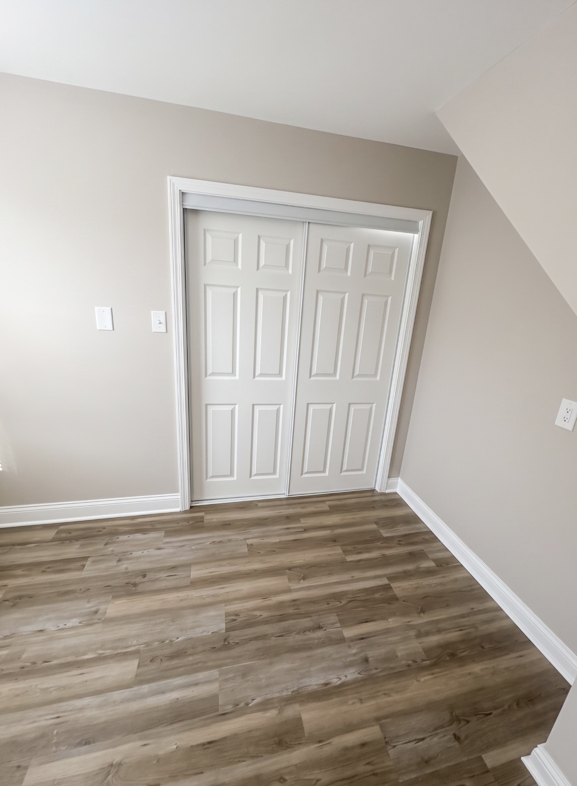 Finished bedroom with closet doors and vinyl plank flooring